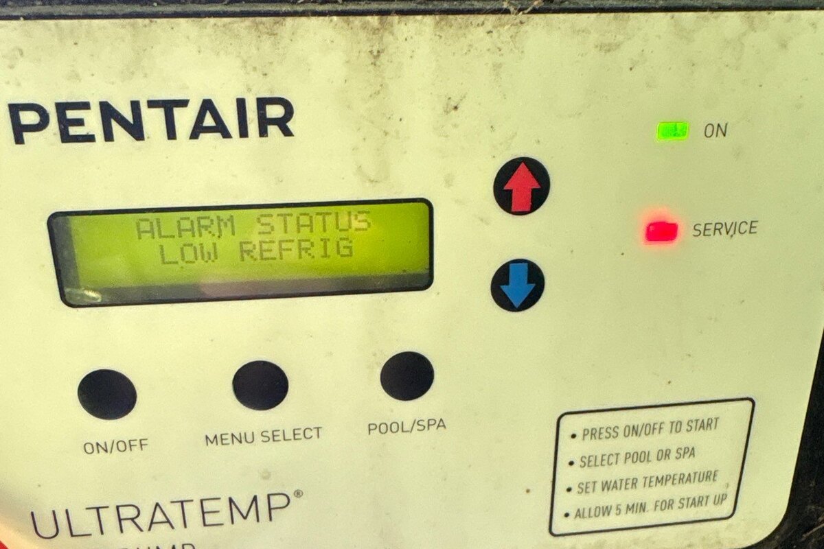 Pentair UltraTemp pool heat pump control panel reading ALARM STATUS LOW REFRIG with the red service light lit